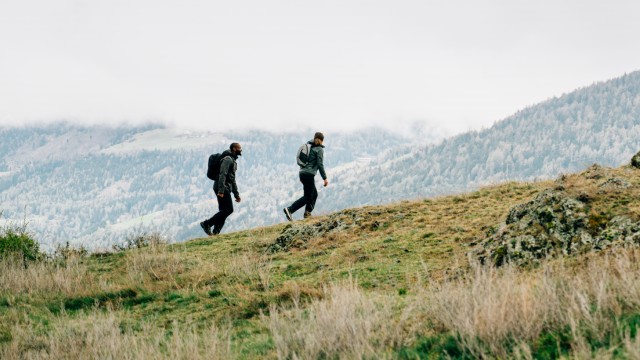 Kobieta w letnim outdoorowym ubraniu balansuje na kamieniach nad morzem