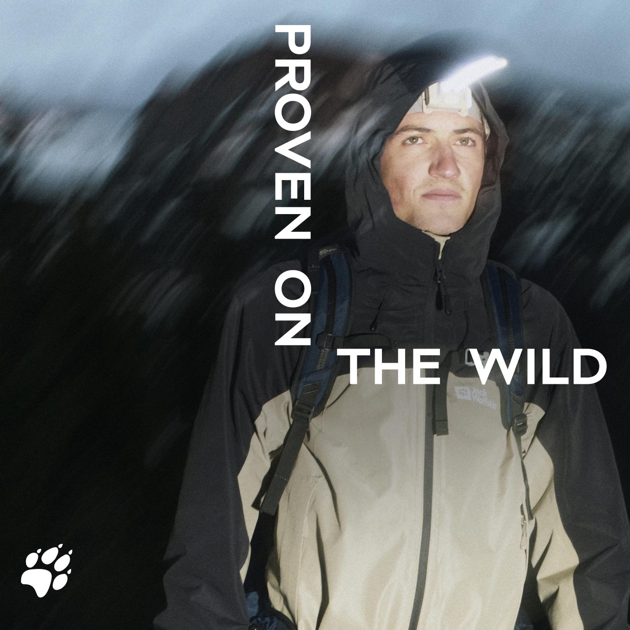 Osoba w kurtce z kapturem stoi na świeżym powietrzu nocą i ma na sobie czołówkę. Tekst brzmi „Proven on the Wild”