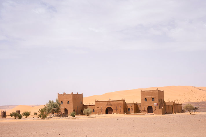 Brązowy budynek z palmami na pustyni
