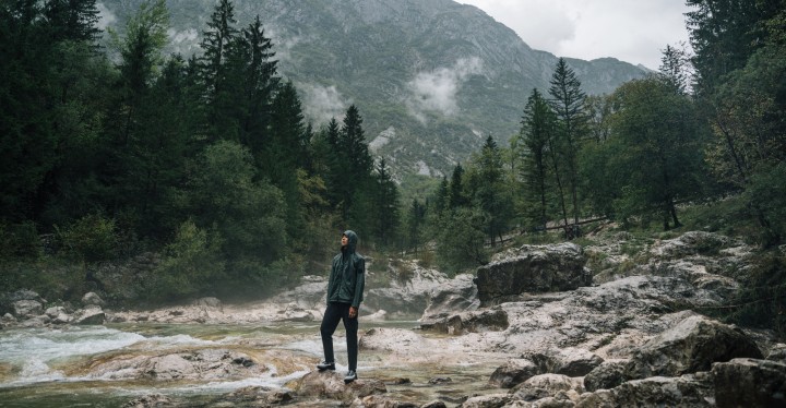 Mężczyzna w outdoorowym ubraniu stojący na tle mglistego górskiego krajobrazu