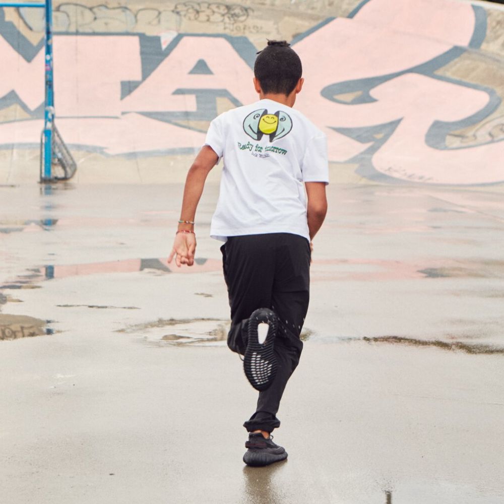 Chłopiec biega po asfalcie – w tle graffiti