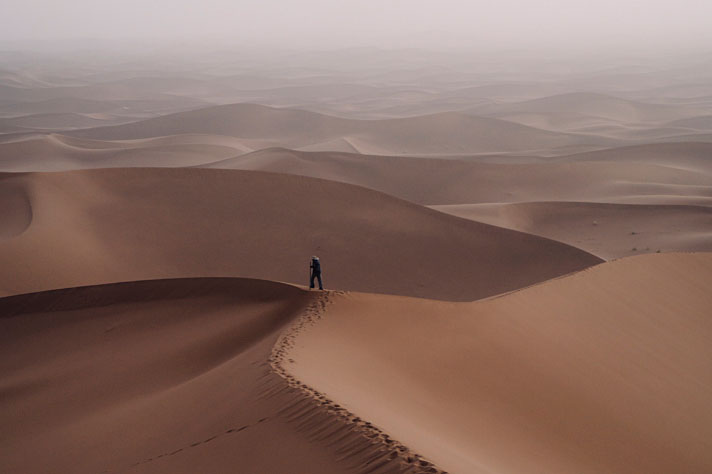 Mężczyzna stojący na wydmie na pustyni