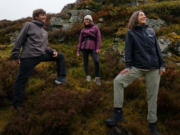 Zwei lachende Frauen in einer Berglandschaft bauen ein Zelt auf