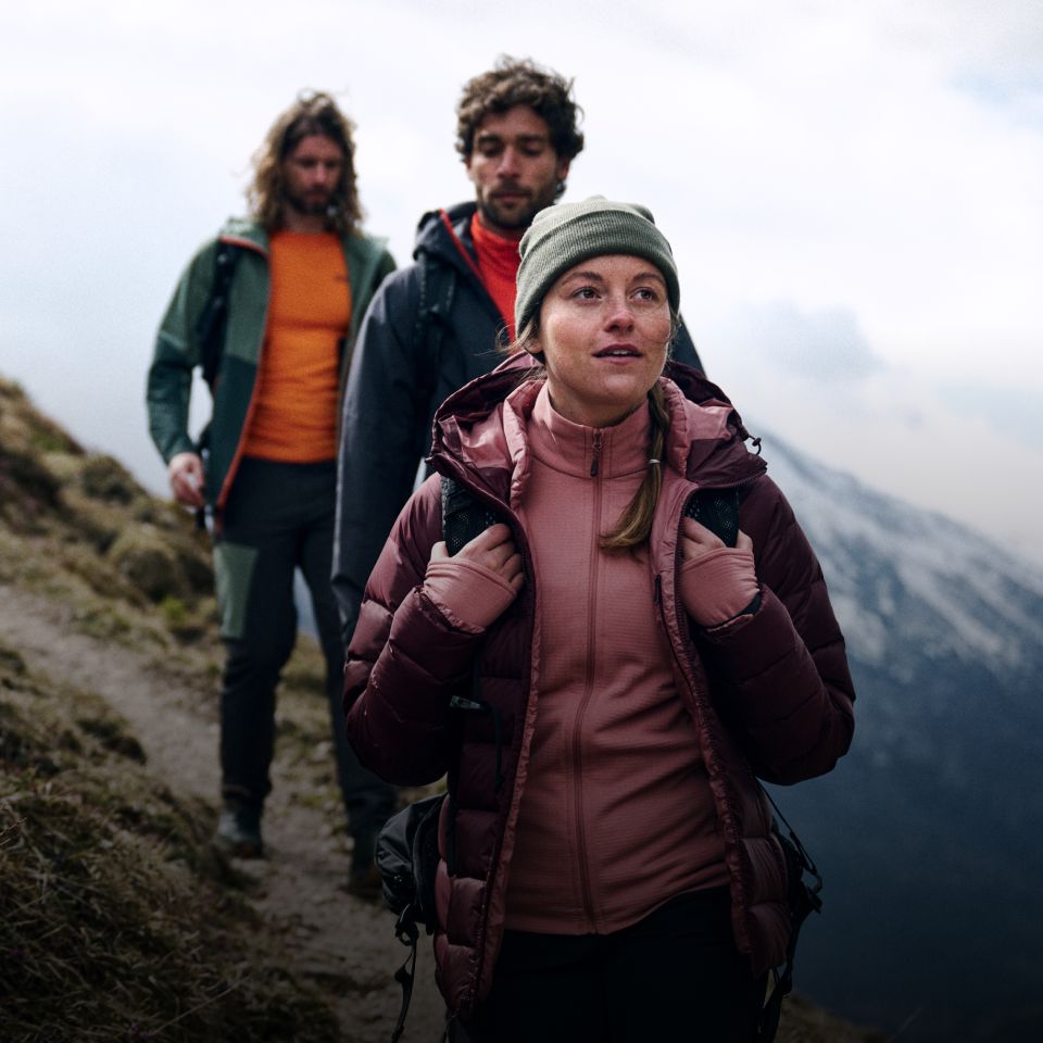Trzech turystów w ciepłych ubraniach wędrujących po górach