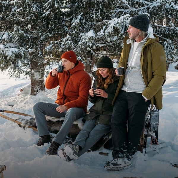 Trzy osoby siedzące na sankach na śniegu